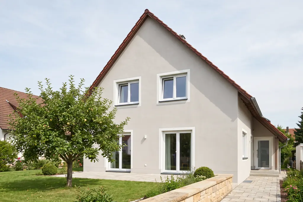 Wohnhaus im Stil der 1950er-Jahre mit rotem Ziegeldach, heller Putzfassade und weißen Fenstern