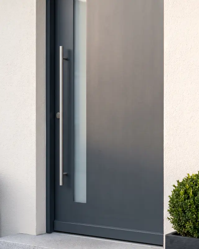 Detail einer anthrazitfarbenen Haustür mit Edelstahl-Stangengriff und schmalem Glasstreifen